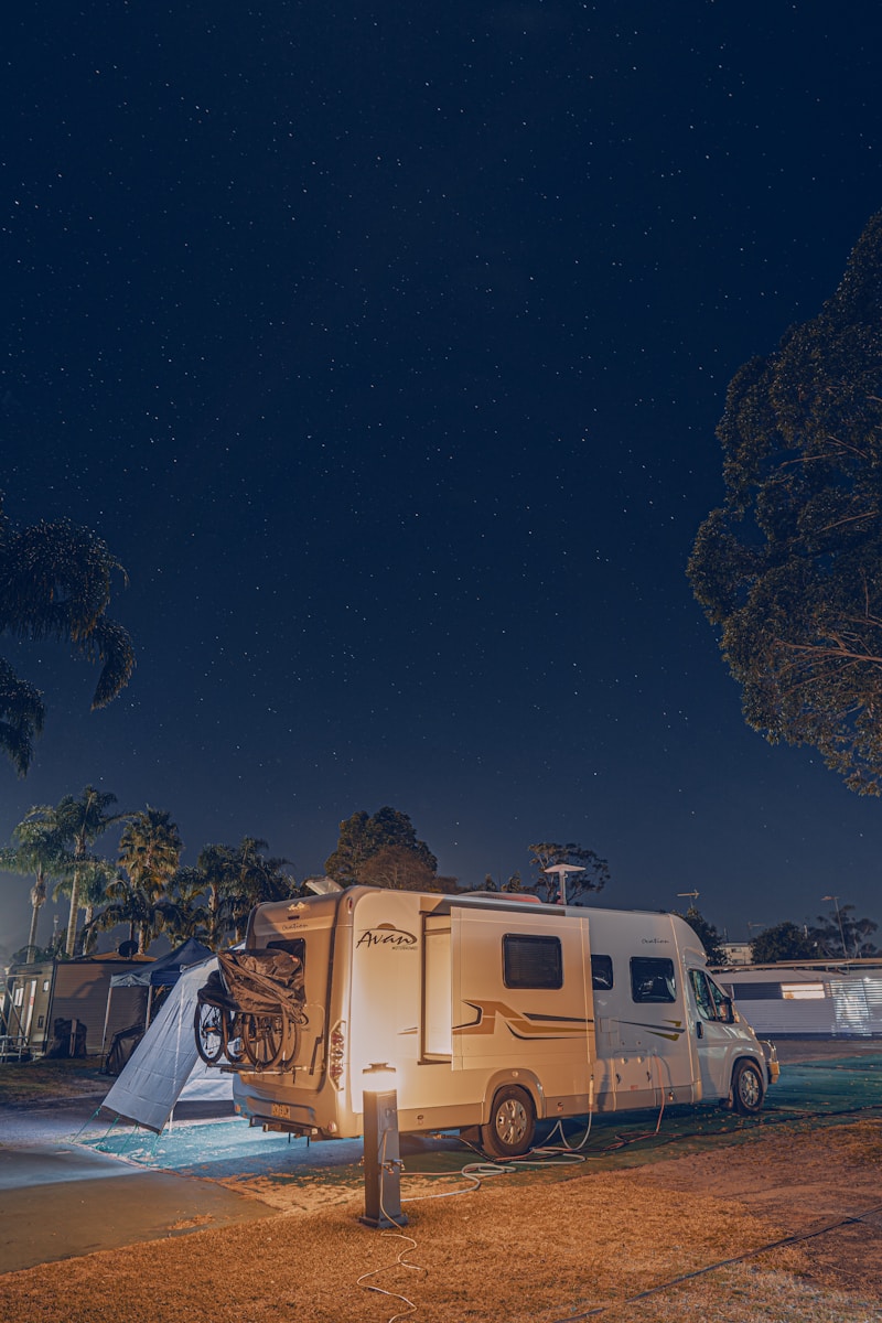 a camper with coverage for your rv parked next to a tree at night