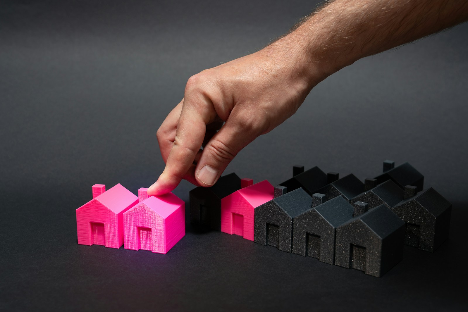 A hand is pointing at a small pink house